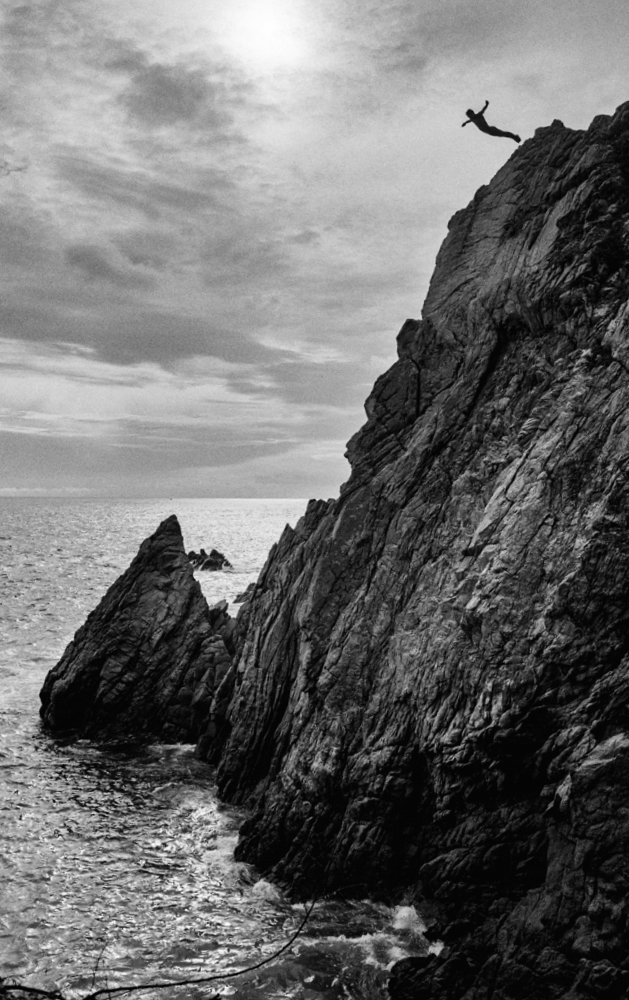 Saisissante photographie en noir et blanc du photographe Hans Silvester : un plongeur sautant du plus haut d'une falaise à Acalpuco