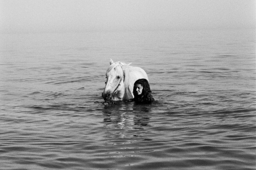 Une jeune fille se baigne avec son cheval Camargue
